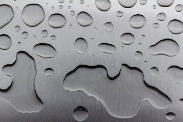 Abstract art texture background of water drops on an exterior brushed stainless steel surface following rain precipitation