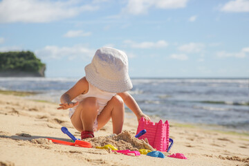 Summer vacation. Adorable toddler girl playing with beach toys on the sandy beach.