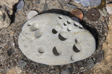Obraz na płótnie Canvas 複数の穴が開いた石と複数の硬貨