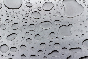 Abstract art texture background of water drops on an exterior brushed stainless steel surface following rain precipitation