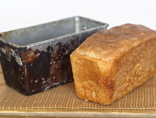 Freshly baked diet rye bread with a baking dish on a wooden table with a gray background.