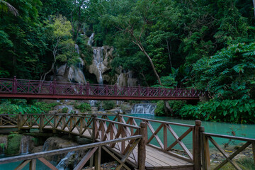 Kuangsi waterfall has two distinct sections. From high on the mountain ridge, the water falls down seven steep rock cliffs into the pool under this bridge  in Luang Prabang, Laos.