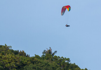 Orange and yellow paraglider on clear blue sky
