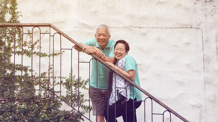 Happy vacation trip for Asian elderly couple resort wood stair with green vine plant