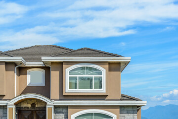 A perfect neighborhood. Houses in suburb at Summer in the north America. Fragment of a luxury house with nice window over blue sky.