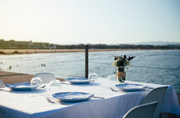restaurant table with white tablecloth on the terrace by the sea