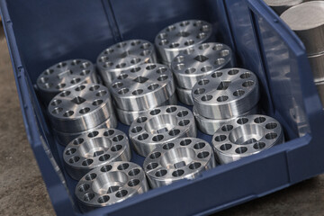 Cylindrical steel metal part with round holes made on lathe in blue case. Metal industry products, workpieces. Steel products to automotive industry. Billet obtained on lathe from steel and cast iron