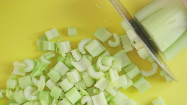 a woman prepares slices on a cutting board ingredients for a celery smoothie and puts them in a blender bowl