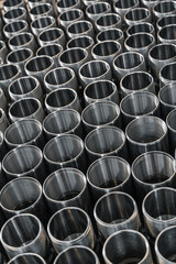 Closeup pattern of shiny circular precision stainless steel industrial machine parts arranged in rows on pallet. Steel products to automotive industry.Billet obtained on lathe from steel and cast iron