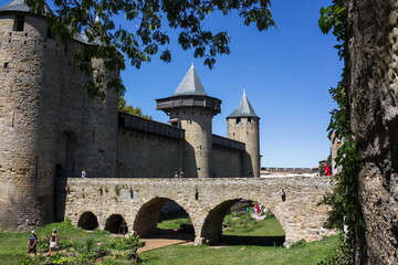 Fototapeta na wymiar Powerful fortifications and bastions of Carcassonne Castle. Beautiful conical blue roofs of towers. Bridge and entrance to the central fortress