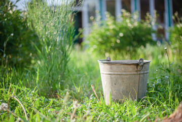 Old rusty bucket on the garden house yard close up background. © Natali