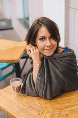 Young girl with a cup of cocoa sits on a summer terrace in the cafe with her friend