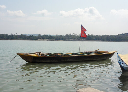 A single boat on the center of river with the flag of Nepal 