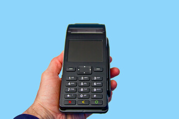 Hand is holding a credit card payment terminal on blue background.