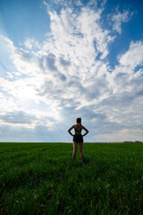 Fototapeta na wymiar Healthy lifestyle concept. Young attractive woman in sportswear does stretching her hand before training on the nature against a blue sky. Muscle warming