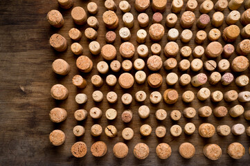 Wine corks of different sizes, standing upright on an old wooden surface. Background for liquor.