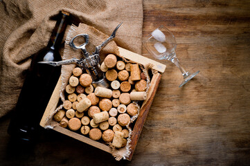 Wine corks of different sizes, a corkscrew, a bottle of wine and a glass shot on an old wooden...
