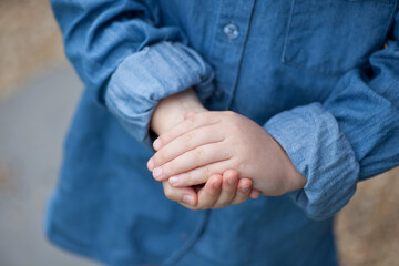 A small young child's hands clasped together