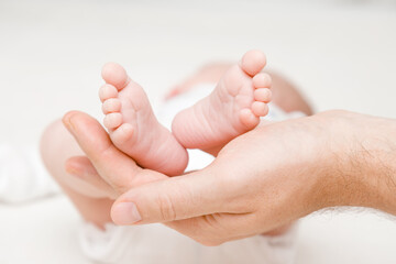 Newborn cute feet in young father palm. Lovely, emotional moment. Closeup. Front view.