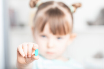 Obraz na płótnie Canvas Little girl holding a pill addict. Focus on hands