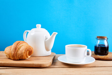 breakfast with croissants.Fresh crispy croissants and coffee on a blue background and wooden table