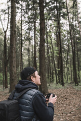 Traveler man relaxing in forest with photo camera, backpack. Travel lifestyle concept vacations outdoor.