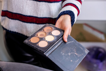 The makeup artist is holding a palette with makeup shadows. Nude and fashionable shades, for sculptural correction, many times already used. Selective, back and front  focus, art noise on the photo