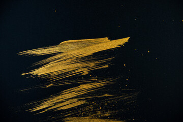 strokes with golden paint brush on black paper.