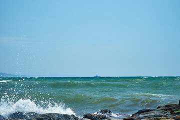 Image of the sea shore. In the background is a warship.