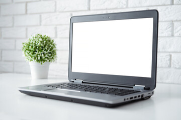 Mock-up laptop with blank white color screen on white table. Close up laptop. Home or office interior.