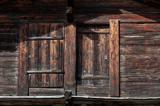 Background and wood texture from a wall of an old wooden house with doors and windows