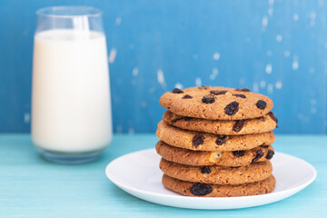 Fototapeta na wymiar Cookies with raisins and glass of milk on blue background