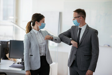  Businessman and businesswoman with medical mask in office. Greetings in Covid-19 time.