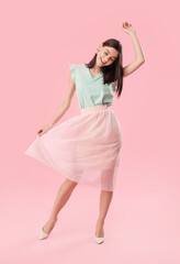 Beautiful young woman dancing against color background