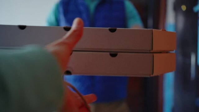 POV delivery man comes to apartment and gives customer order, paper package and pizza boxes. food Delivery during quarantine.