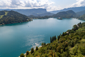 Fototapeta premium Lake Bled with a small island in the middle and surrounded by mountains covered with green forest. Slovenia, Bled.