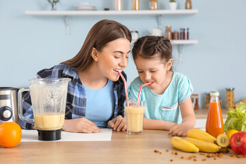 Mother and little daughter with healthy smoothie in kitchen