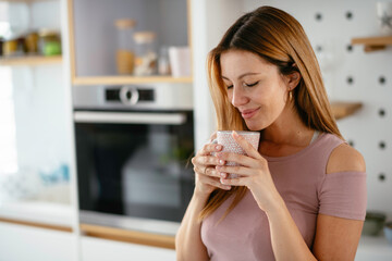  Beautiful woman drinking coffee in the kitchen. Young woman enjoy at home.