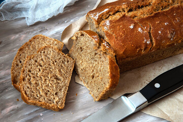 Freshly baked homemade sourdough bread, sliced on gray background