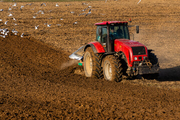 Tractor plows the land during harvest at sunset