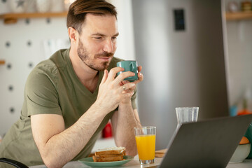Handsome man preparing breakfast at home. Young man drinking coffee in kitchen.	

