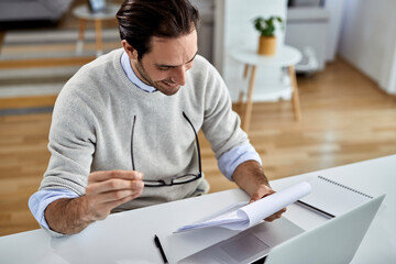 Happy businessman reading reports while working at home.
