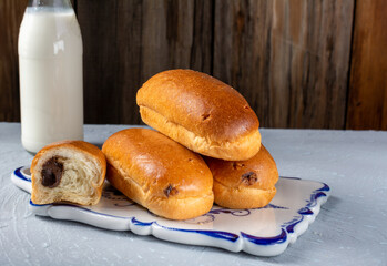 Breakfast rolls with chocolate filling and milk on a wooden rustic background