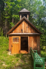 Fototapeta na wymiar Small wooden chapel with bench and forest on the background above Vrbno pod Pradedem town in Czech republic