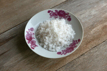 Selective focus of coconut flakes in a plate on a wooden background.