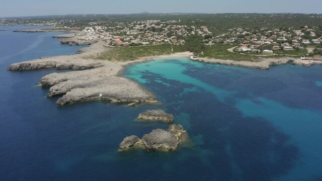 Crystal Clear Blue Water Of Binebeca Beach And View Of Town In Menorca, Spain. Empty Beach During The Coronavirus Pandemic.- aerial drone