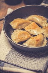 Dumplings stuffed with meat sprinkled with fresh herbs on a cast iron skillet, top view. 