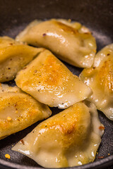 Dumplings stuffed with meat sprinkled with fresh herbs on a cast iron skillet, top view. 