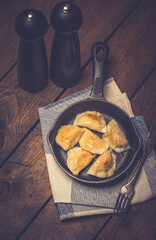 Dumplings stuffed with meat sprinkled with fresh herbs on a cast iron skillet, top view. 