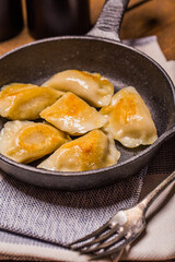 Dumplings stuffed with meat sprinkled with fresh herbs on a cast iron skillet, top view. 